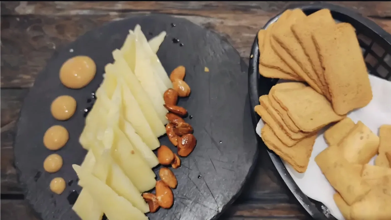 Queso con acompañamiento y salsa sobre pizarra