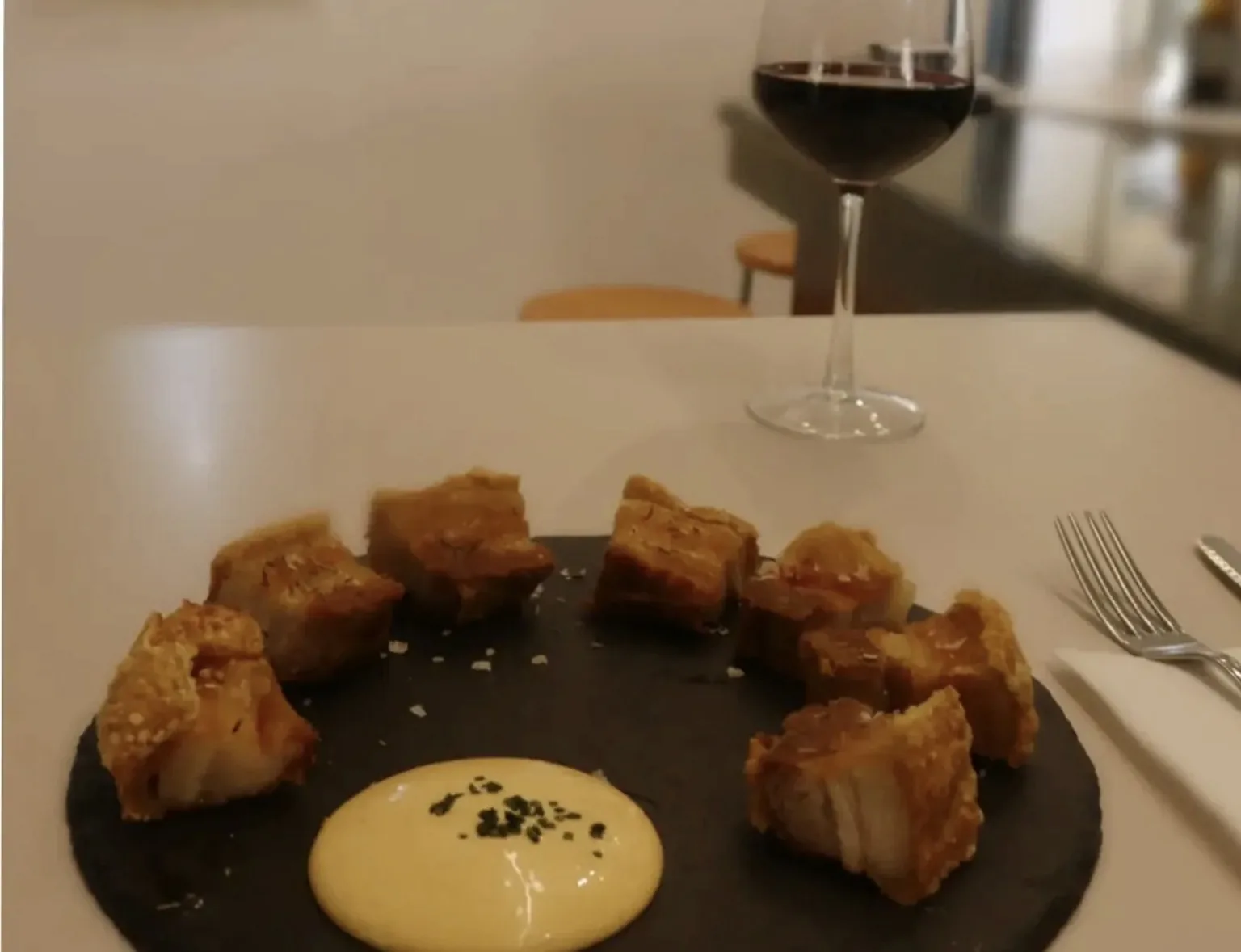 Plato de torreznos junto a una copa de vino